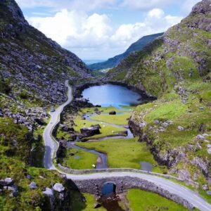 Winding mountain road beside lake in scenic Irish valley