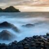 Giant’s Causeway with smooth misty waves at sunset in Northern Ireland