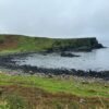 Rocky coastline with green cliffs on a cloudy day in Northern Ireland